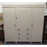 An Edwardian cream painted triple wardrobe, the central section with a panelled door, over three