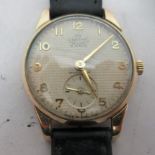 A Smith DeLuxe 9ct gold cased wristwatch, faced by a textured Arabic dial, incorporating