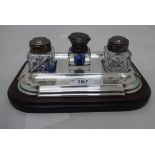 An Art Nouveau glass inkwell with an embossed white metal cap; an Art Deco inspired silver plated