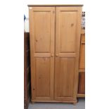 A modern pine twin door wardrobe, enclosing two hanging rails, on a plinth and bun feet  71"h  35"w