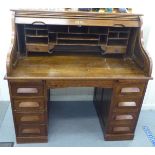 An early 20thC stained and panelled oak rolltop desk, the rising tambour front enclosing a fitted