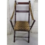 A modern painted mahogany, folding bedroom chair with leopard print straps and a stud upholstered