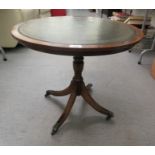 A Reprodux mahogany pedestal occasional table with a green hide scriber inset top, raised on splayed