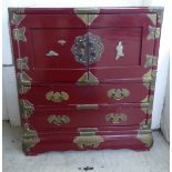 A mid 20thC Chinese red painted and brass mounted table cabinet with an arrangement of drawers,