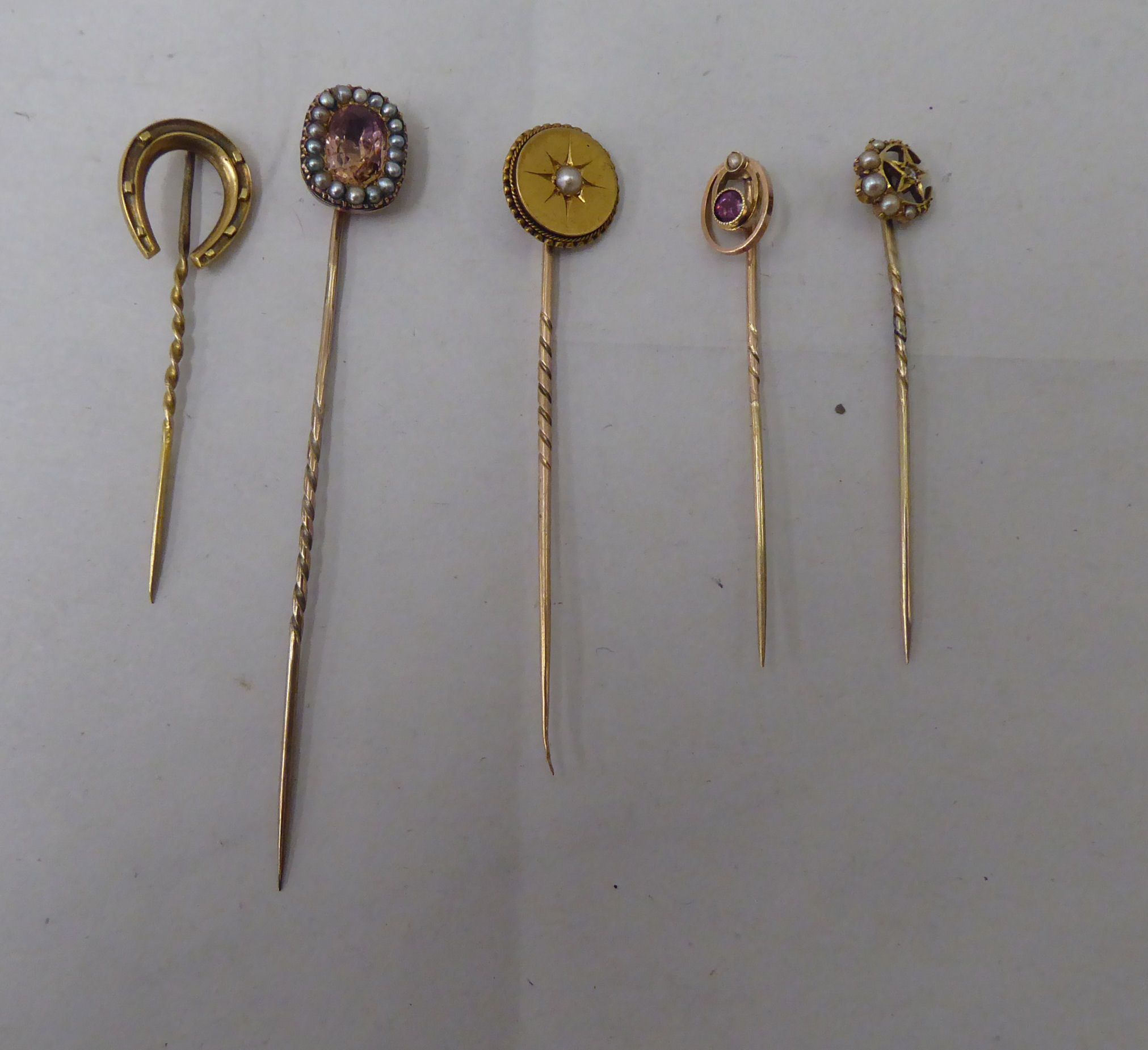 Five dissimilar gold and yellow metal stickpins: to include an 18ct gold example, incorporating a
