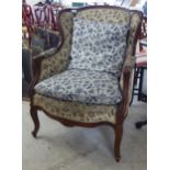 An early 20thC mahogany showwood framed salon chair, upholstered in floral patterned fabric,