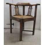 A mid/late 19thC oak and elm framed corner chair, the drop-in woven rush seat raised on square legs