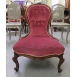 A late 19thC lady's walnut showwood framed waisted balloon back chair, upholstered in pink dralon,