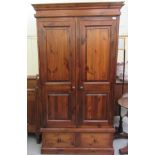 A modern stained pine wardrobe with two panelled doors and two base drawers, on a plinth  76"h  42"w