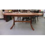A modern teak dining table with round ends, raised on splayed legs  30"h  56"L extending to 76"L