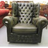 A modern button upholstered, faux green hide wingback arm chair, on casters