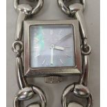 A lady's Gucci wristwatch, the strap fashioned in stainless steel as a horses' bit, faced by a baton