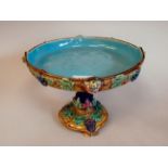 A late 19thC majolica comport, decorated in colours with mounted cupid masks and fruiting vines  7"h