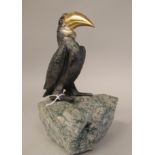 A cast tri-coloured metal model, a Pelican, perched on a piece of mottled green, rough-cut stone