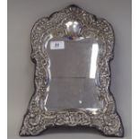 A late 19thC bevelled dressing table mirror, set in an embossed rococo decorated white metal