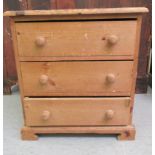 A modern stained pine three drawer bedside chest, on a plinth  23"h  20"w
