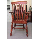 An early 20thC stained beech framed grandfather chair with a solid seat raised on turned legs