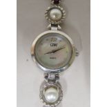 A ladies silver bracelet watch, set with alternating pearls and garnets, faced by a baton dial