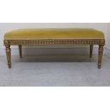 An early 20thC Continental carved giltwood framed long stool, the braided yellow fabric