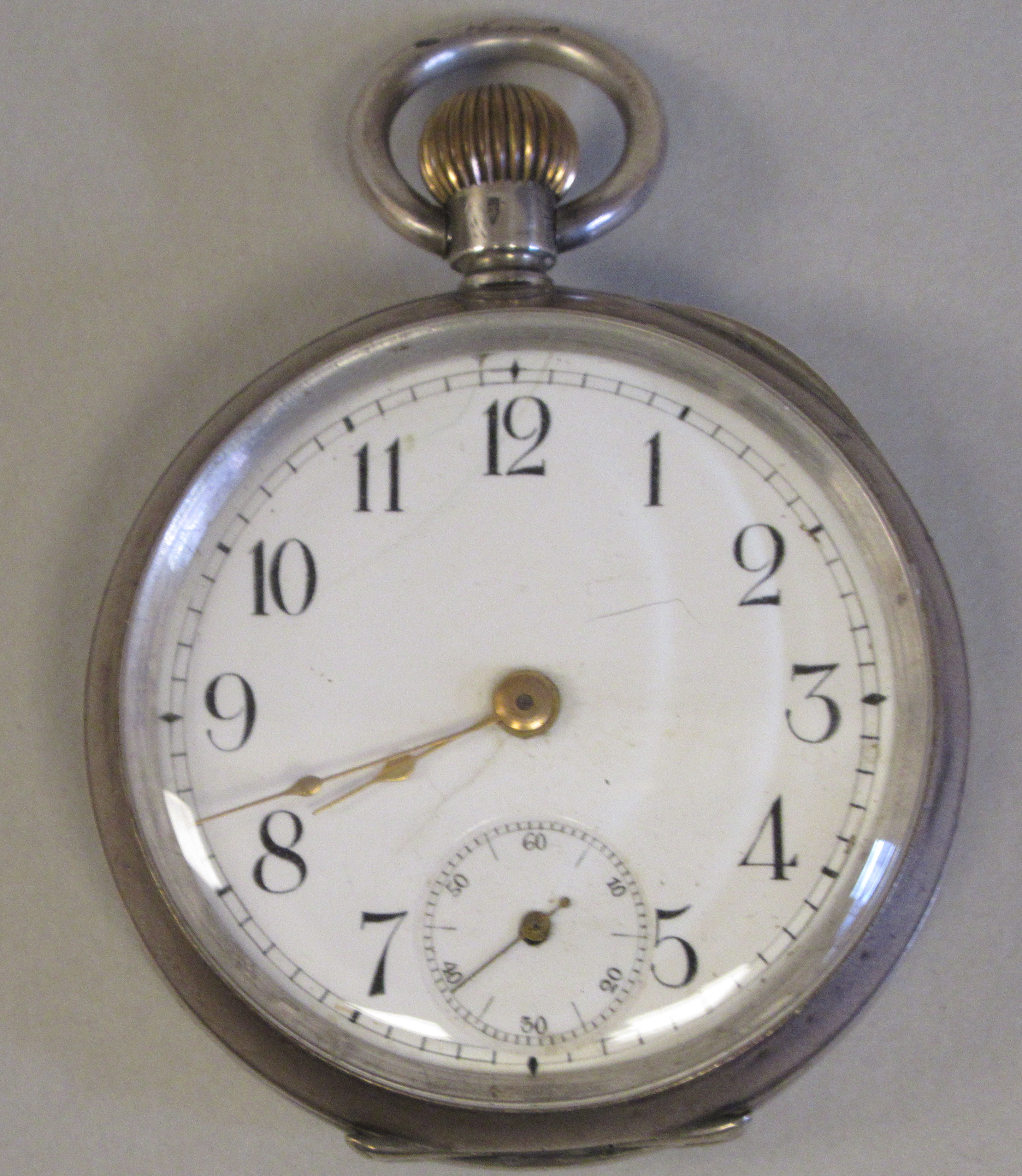 An Omega (935) silver coloured metal cased pocket watch with an engine turned back, faced by a white