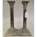 A pair of loaded, bead bordered silver candlesticks, each with a detachable sconce in a Corinthian