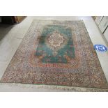 A Persian rug decorated with a central floral motif, bordered by stylised foliage on a multi-