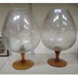 A pair of novelty 'oversize' amber coloured and clear glass brandy balloons  16"h