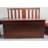 A child's modern mahogany finished bedroom bench with a lath back, over a hinged seat, on a