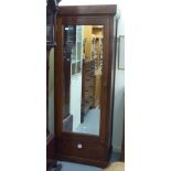 A modern teak single section wardrobe with a mirrored door, over a single drawer, raised on