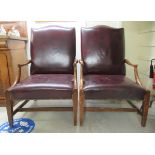 A pair of 20thC stained beech framed open armchairs, the stud upholstered maroon hide cushioned back