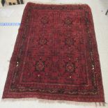 A Persian woollen rug with geometric design, on a deep red ground  80" x 48"