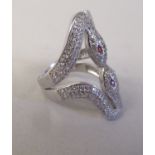 A silver coloured metal and cubic zirconia set, double snake head ring with ruby set eyes