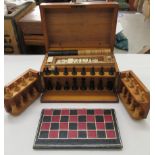 An early 20thC partially fitted pine box, containing a chessboard, thirty-two boxwood chessmen and