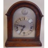 An early 20thC round arch, oak cased bracket clock; the gong strike movement faced by a silvered and