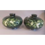 A pair of 20thC moss green enamel vases of squat, bulbous form, decorated in colours with