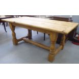 A 20thC bleached pine kitchen table, the planked top with rounded corners, raised on turned,