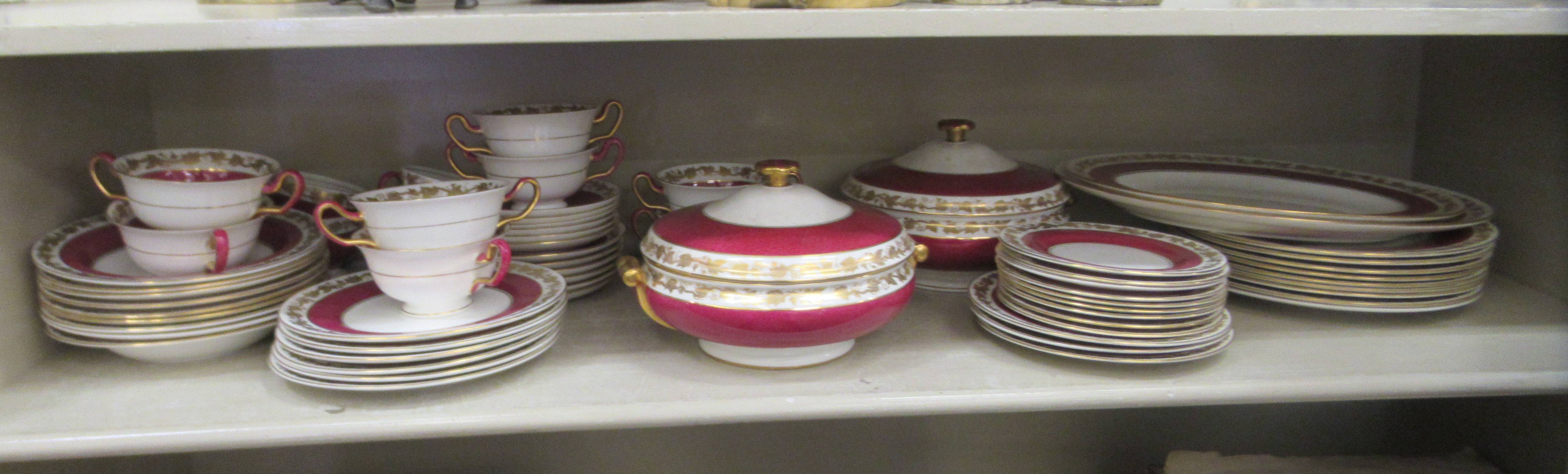 A Wedgwood china dinner service, decorated with maroon bands and a gilded fruiting vine border