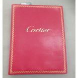 A gilded red hide bound Cartier album, containing printed iconic designs for period clocks and