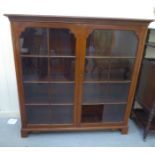 An Edwardian mahogany bookcase with a pair of glazed doors (one panel missing), raised on bracket