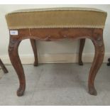 An early/mid 20thC footstool, the cushioned tapestry covered top raised on carved, cabriole legs