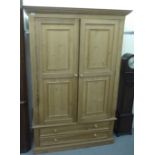 A modern pine wardrobe with a pair of panelled doors, over two long drawers, on a plinth  74"h  50"w