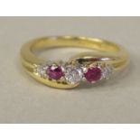 A gold coloured metal crossover ring, set with diamonds and rubies  stamped 18k