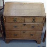 A George III oak bureau with a fall front, two short and two long drawers, raised on bracket feet