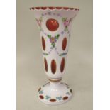 A late 19thC Bohemian cranberry coloured glass trumpet shape vase, the overlaid, cut-away enamel,