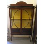 An Edwardian string and ebony inlaid mahogany display cabinet with two glazed doors, raised on