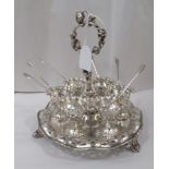 A Continental design white metal six place egg cruet with a wavy edged tray base  8"h  7"dia