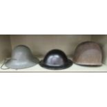 Two Civil Defence painted tin hats; and a military helmet  (Please Note: this lot is subject to