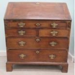 A George III oak bureau, the fall flap over an arrangement of five drawers, raised on bracket