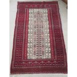 A Turkish rug, decorated with repeating stylised design, on a red ground  38" x 64"