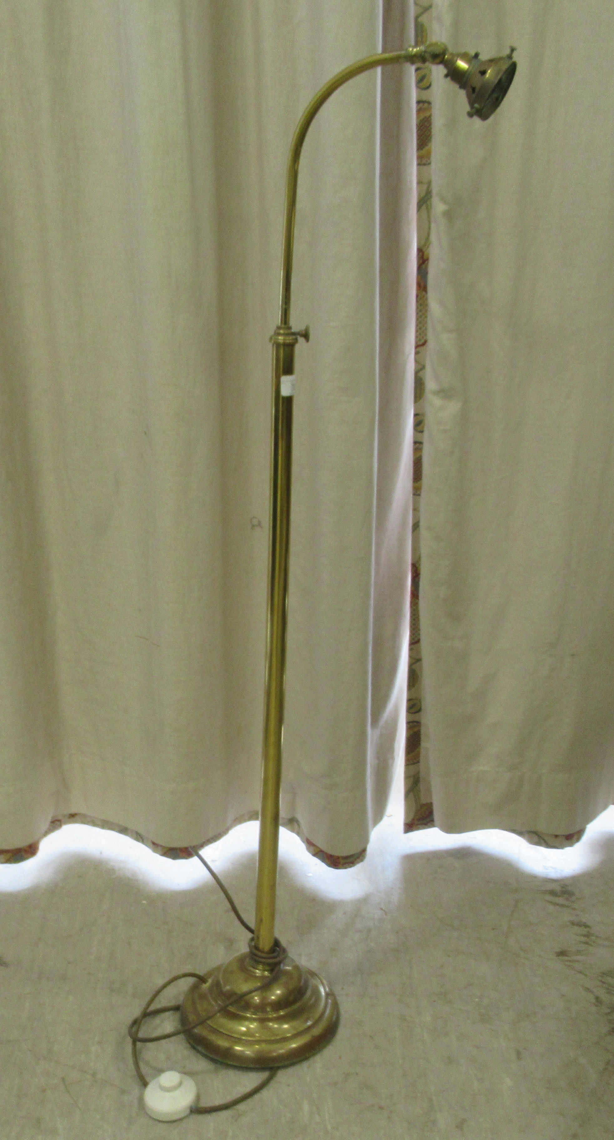 A mid 20thC lacquered brass telescopic standard lamp with an arched arm, accommodating a green glass